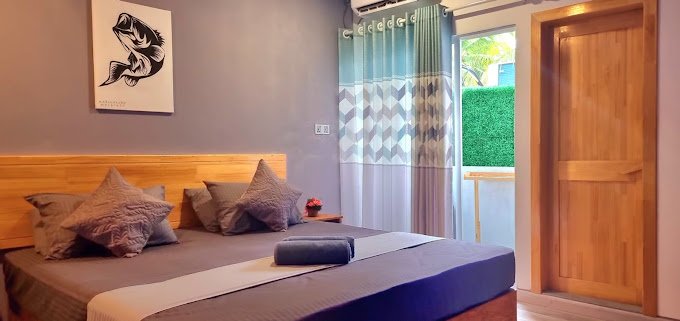 Spacious deluxe double room at Mahchavaru Maldives with balcony and tropical garden view.