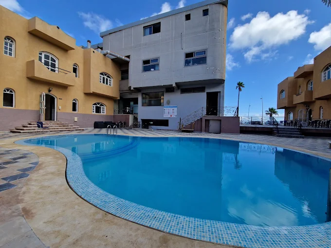 Outdoor swimming pool at Amwaj Hotel surrounded by sun loungers and palm trees