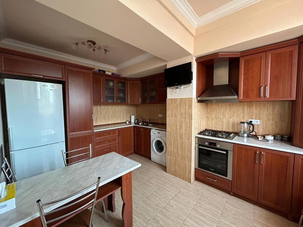 Fully equipped kitchen in LeSi Apartament, Yerevan, Armenia, with stove, refrigerator, and dining area.